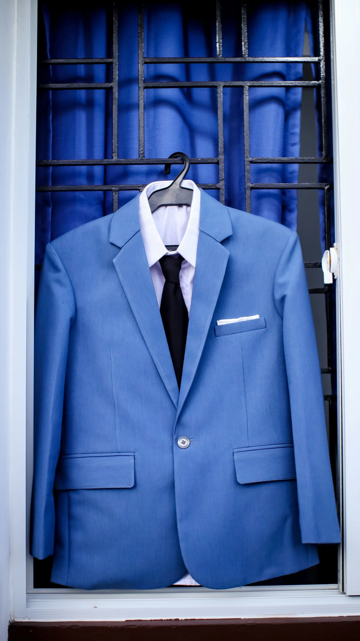 Blue suit jacket with a white shirt and dark tie on a hanger