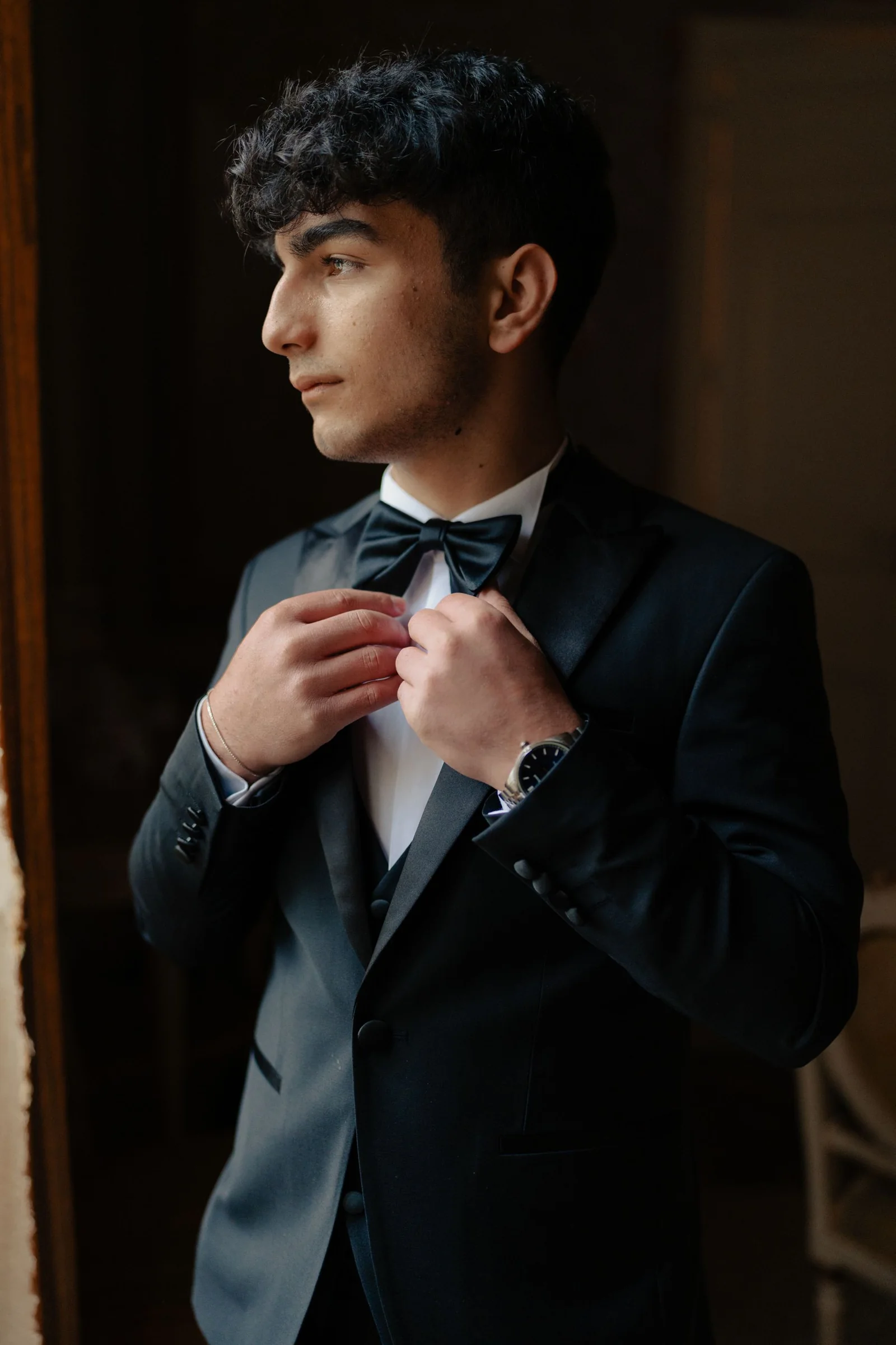 Illustrative young adult adjusting a bow tie in a dark suit