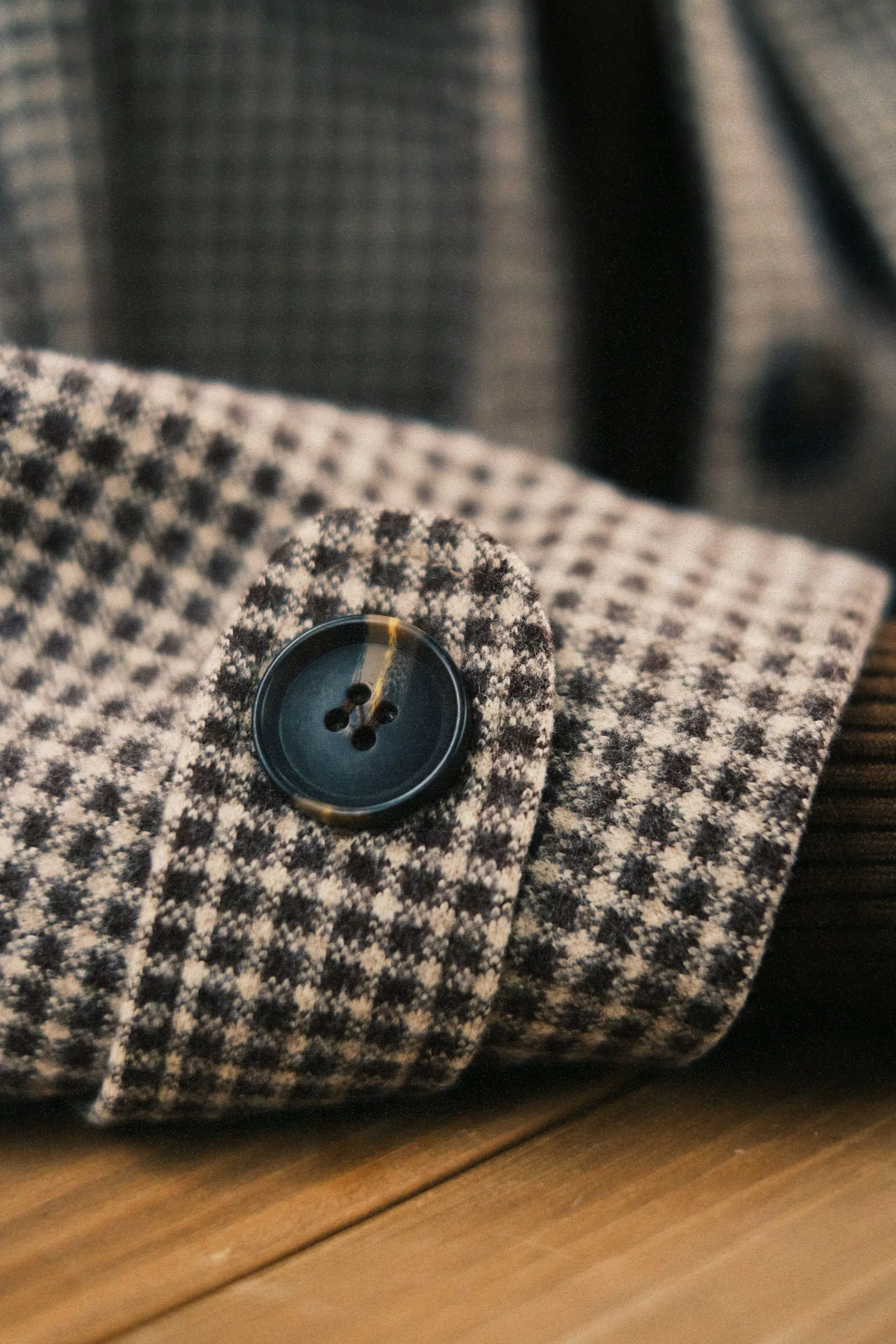 Illustrative houndstooth cuff tab with a dark sewn button