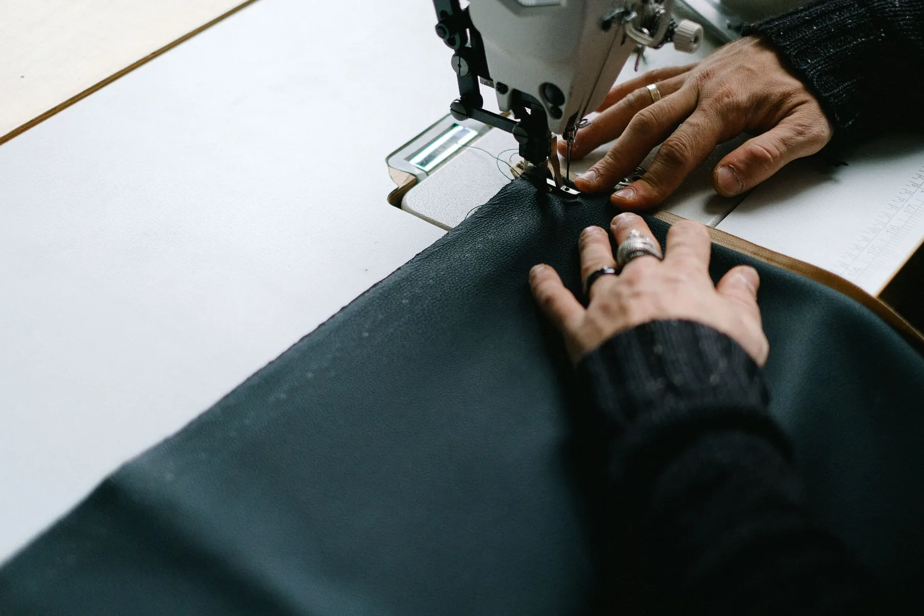 Illustrative sewing machine needle and hands guiding dark cloth