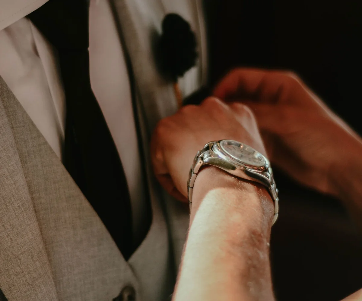 Illustrative hands adjusting a light grey wedding waistcoat